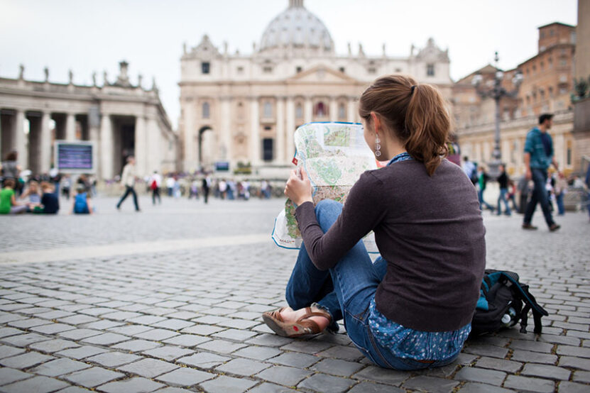 Pretty young female tourist studying a map at St. Peter's square