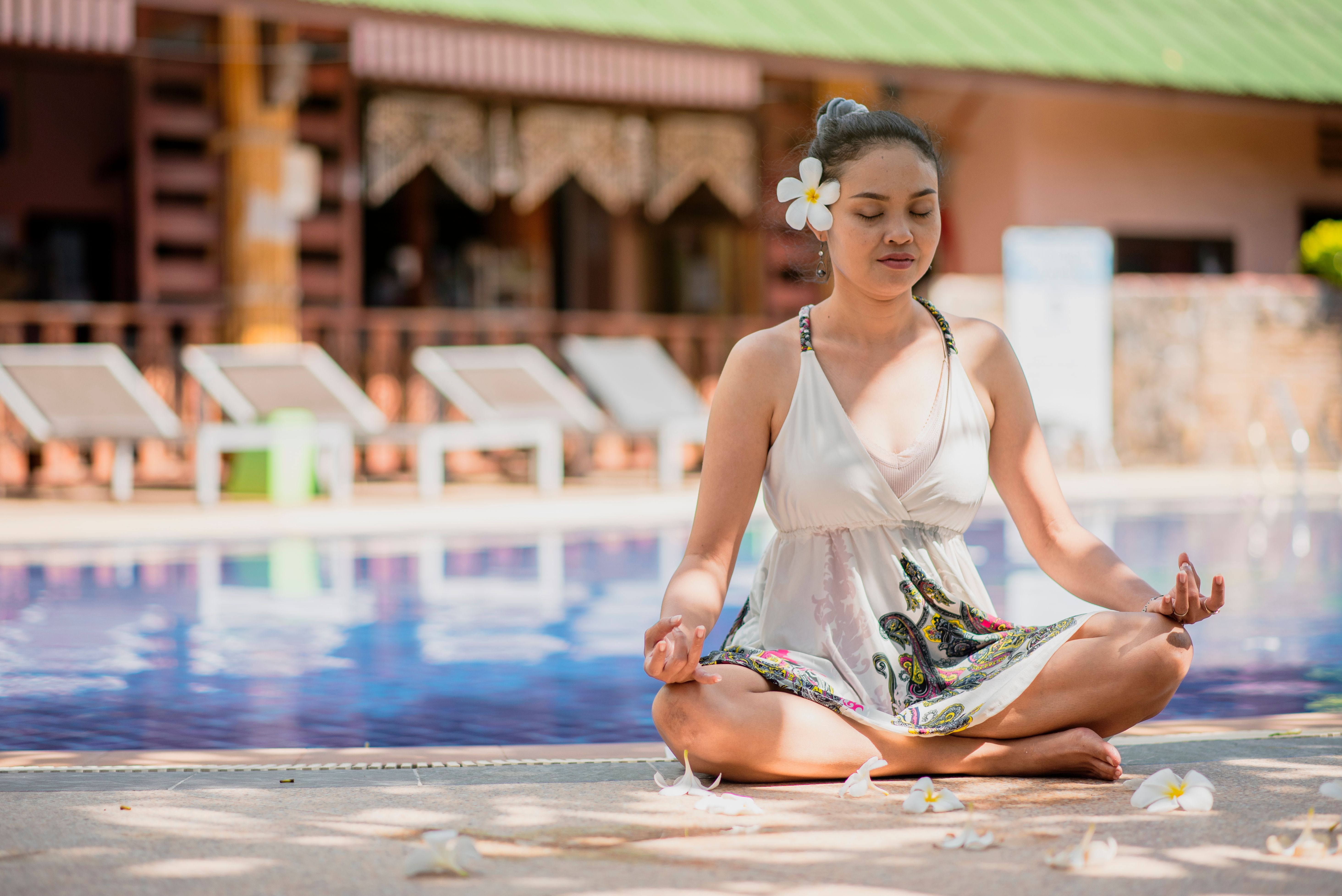 A woman practicing yoga meditation by a luxury pool, embracing relaxation and mindfulness